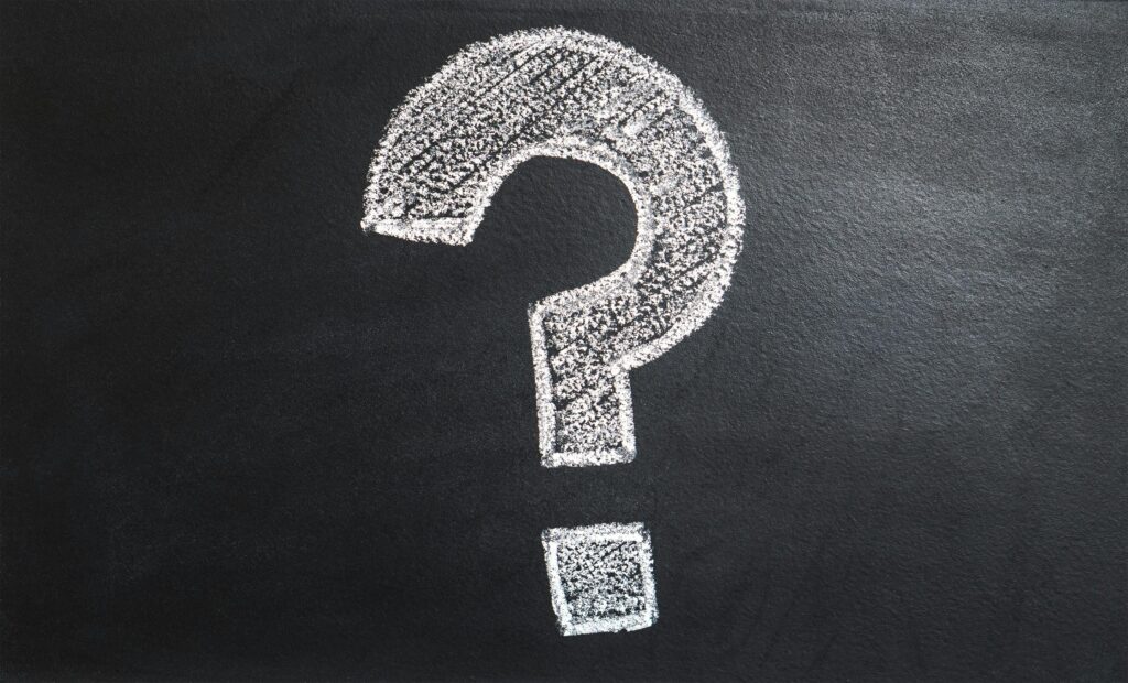 A large white question mark drawn in chalk on a blackboard, symbolizing inquiry or uncertainty.